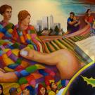 Multicolored wall mural of 4 diverse humans with a multicolored blanket draped over them, held by a large hand. Also green agricultural fields and workers nearby.