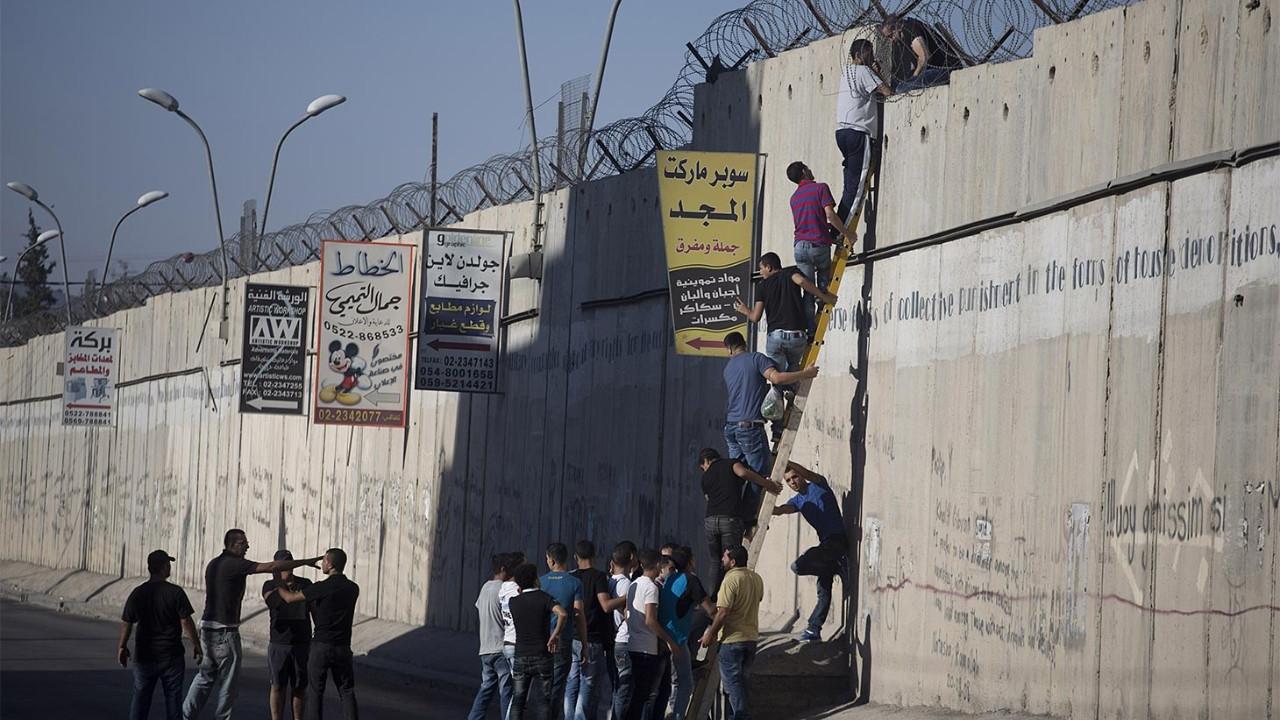 People climbing over barrier in Palestine