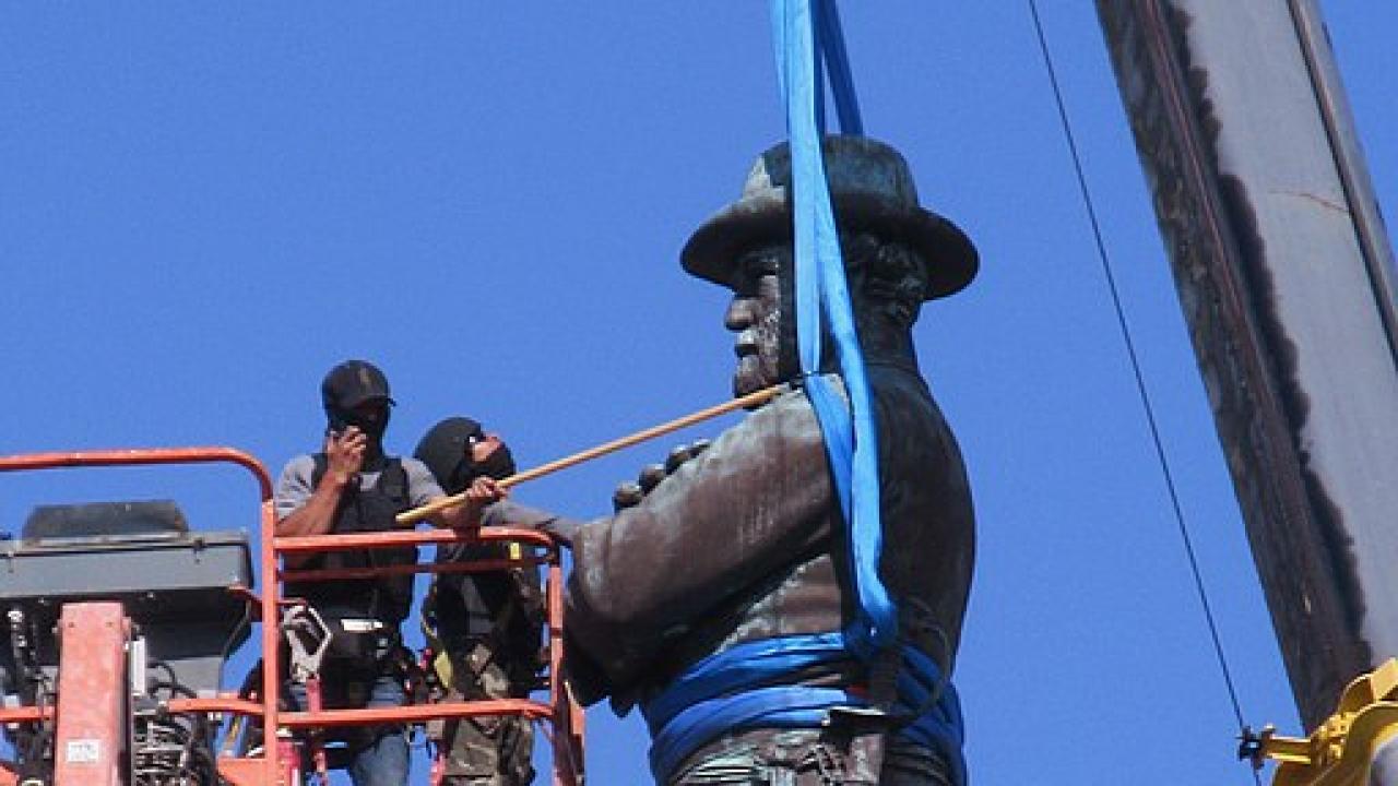 workers in a cherry picker next to statue
