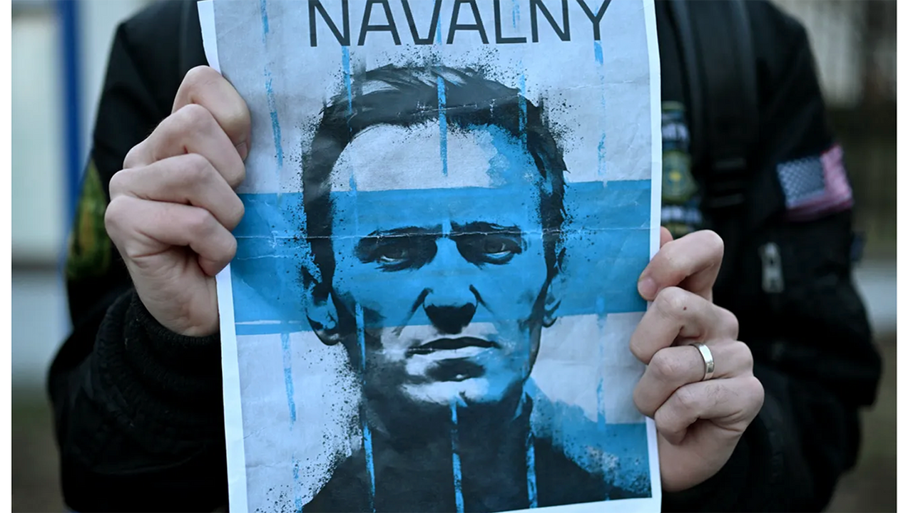 Blue flyer held with human hands displaying a sketch of Alexei Navalny's face 